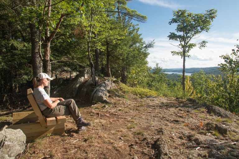 hiker on a wooden bench next to the trail