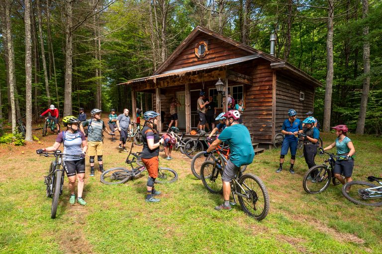 Mountain bikers taking a break next to a cabin in the woods